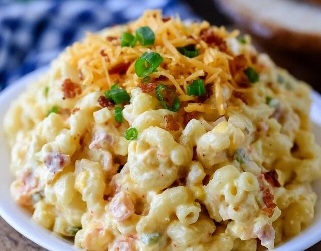 Cheesy bacon macaroni salad in a bowl, elbow macaroni in a creamy dressing with cubes of cheddar, crispy bacon bits, diced celery and red onion, sprinkle of chives