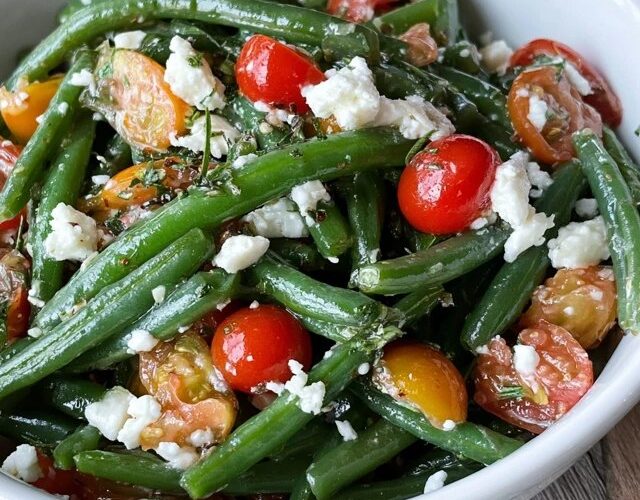 Green bean tomato salad on a platter, crisp-tender blanched green beans tossed with halved cherry tomatoes, crumbled feta, red onion and a lemon vinaigrette, fresh herbs on top