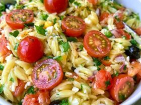 Orzo pasta salad in a bowl, tender orzo with cherry tomatoes, cucumber, red onion, kalamata olives, feta and fresh herbs in a lemon dressing