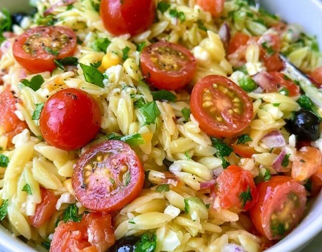 Orzo pasta salad in a bowl, tender orzo with cherry tomatoes, cucumber, red onion, kalamata olives, feta and fresh herbs in a lemon dressing