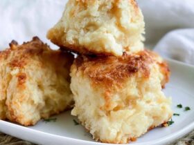 Cheddar bay biscuits piled on a plate, golden fluffy biscuits flecked with cheddar, brushed with garlic herb butter and sprinkled with parsley