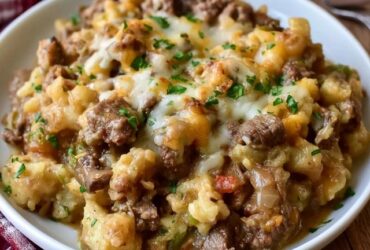 Cheesy beef tater tot casserole in a baking dish, crispy golden tater tots over a layer of cheesy ground beef, melted cheese bubbling between the tots, parsley on top