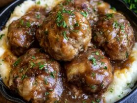 Meatballs and mashed potatoes on a plate, juicy browned beef meatballs smothered in rich brown gravy over a mound of creamy mashed potatoes, parsley garnish