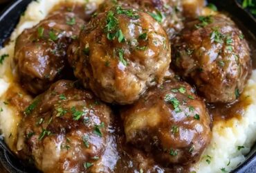 Meatballs and mashed potatoes on a plate, juicy browned beef meatballs smothered in rich brown gravy over a mound of creamy mashed potatoes, parsley garnish
