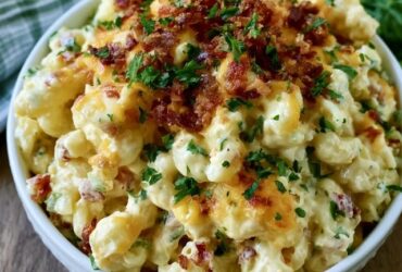 Cheesy bacon ranch pasta salad in a big bowl, rotini coated in creamy ranch dressing with crispy bacon bits, cubed cheddar, cherry tomatoes and chopped green onion on top